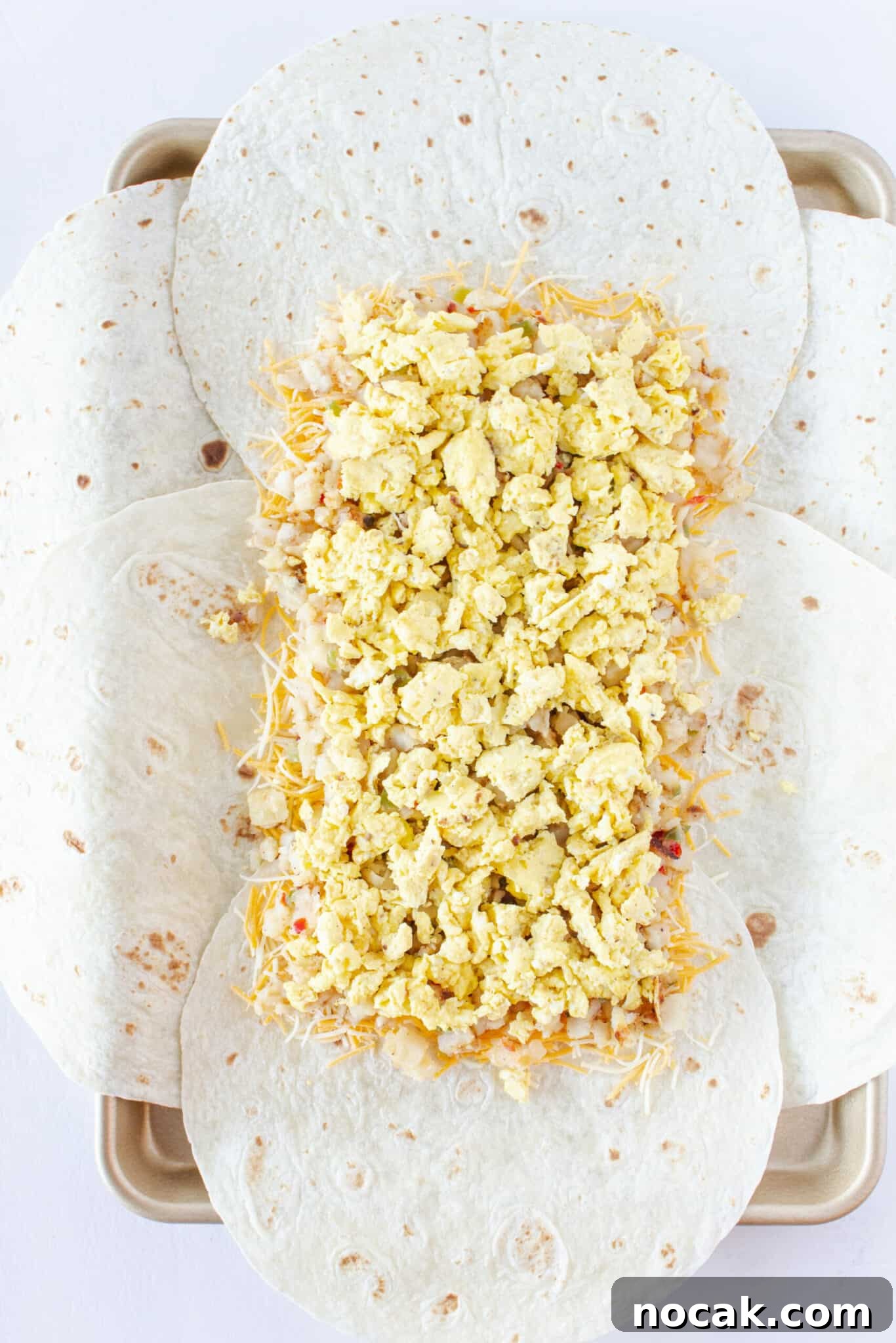Adding the hashbrowns and scrambled eggs to the top of the cheese layer.