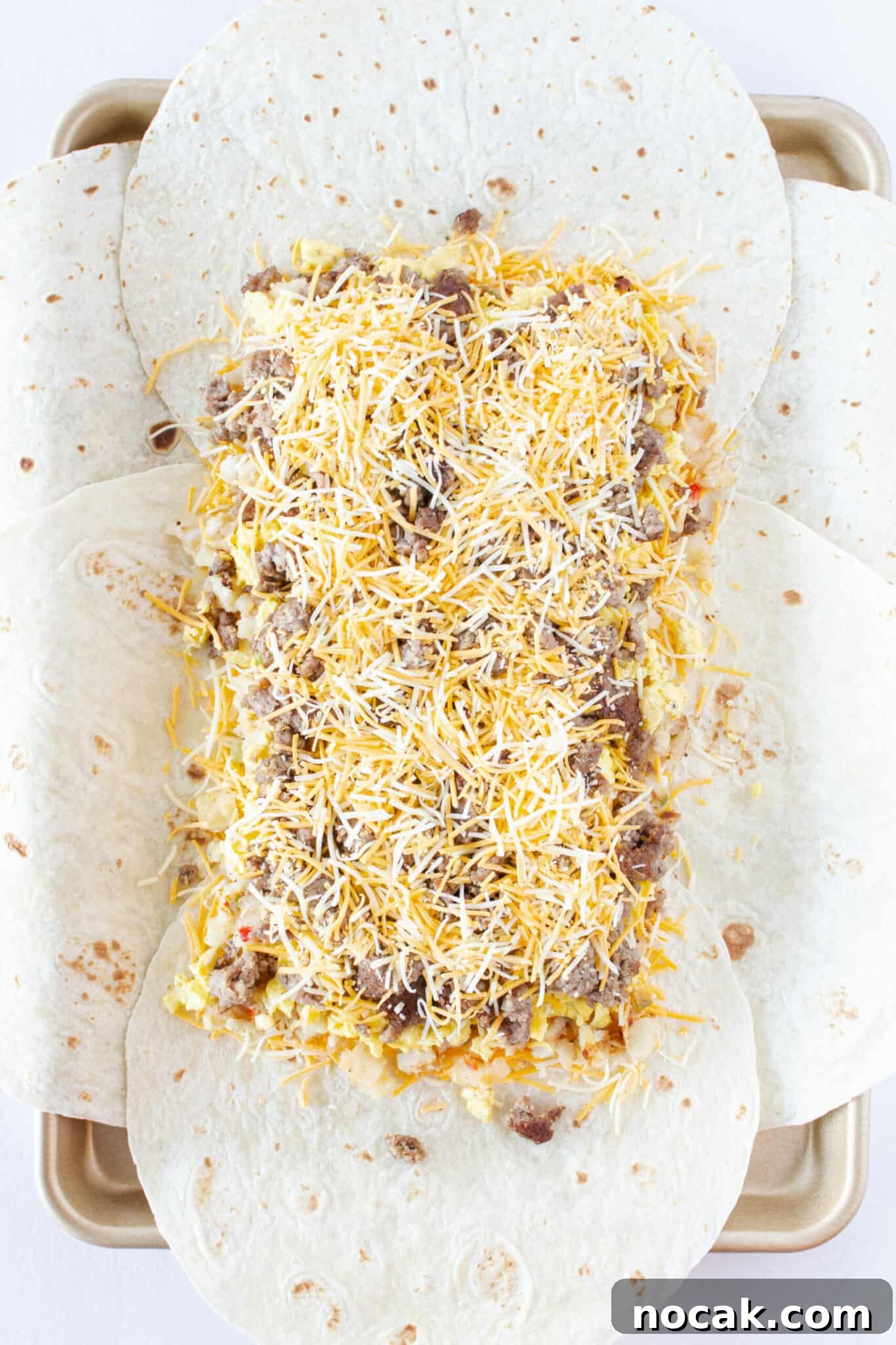 Finishing with a layer of cooked sausage and more cheese.