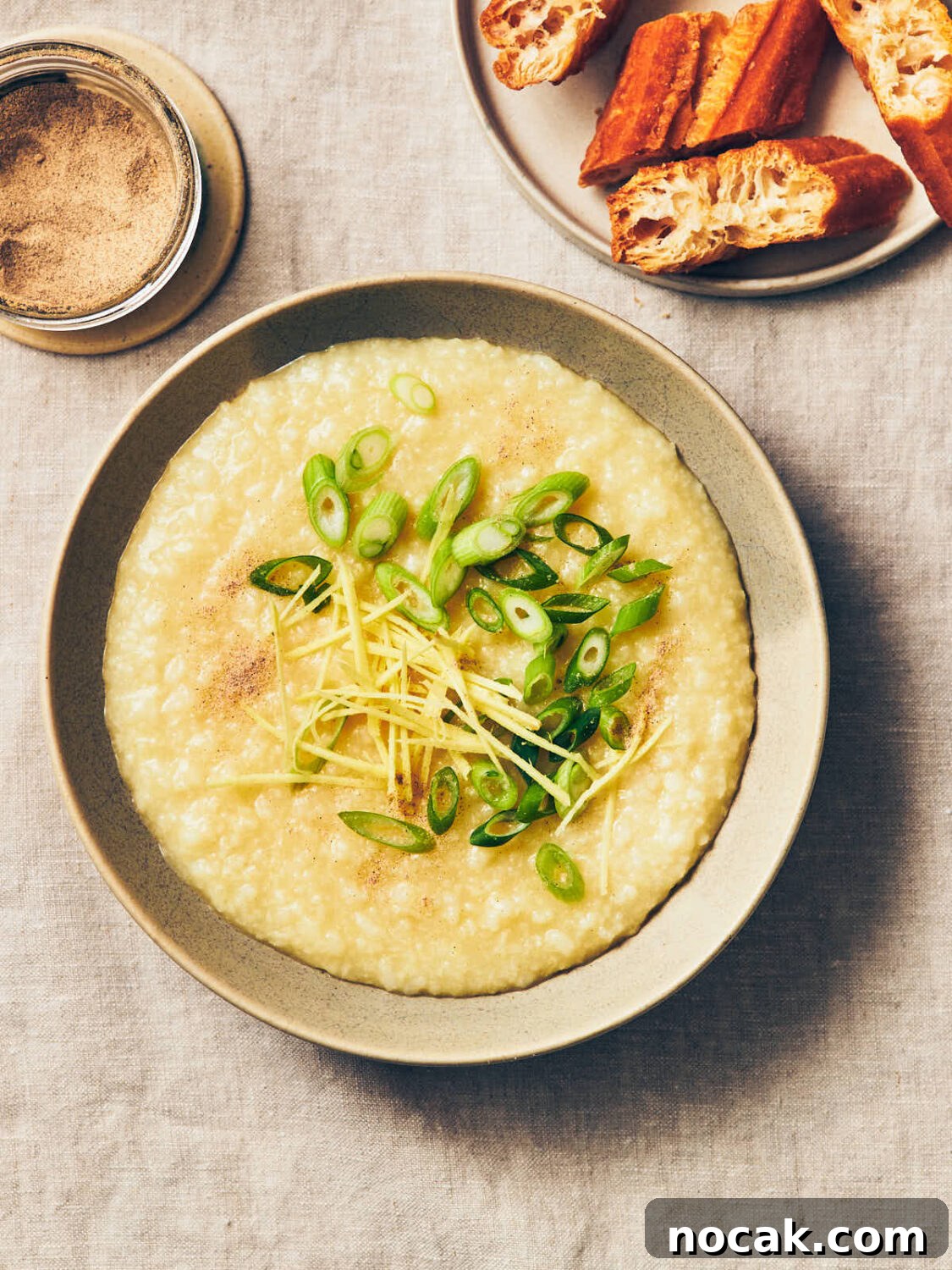 A bowl of vegan congee topped with scallions (green onions), fresh ginger, and white pepper