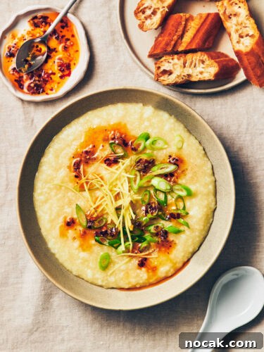 A bowl of vegan congee (rice porridge) topped with chili garlic oil, scallions, ginger, and white pepper on a table