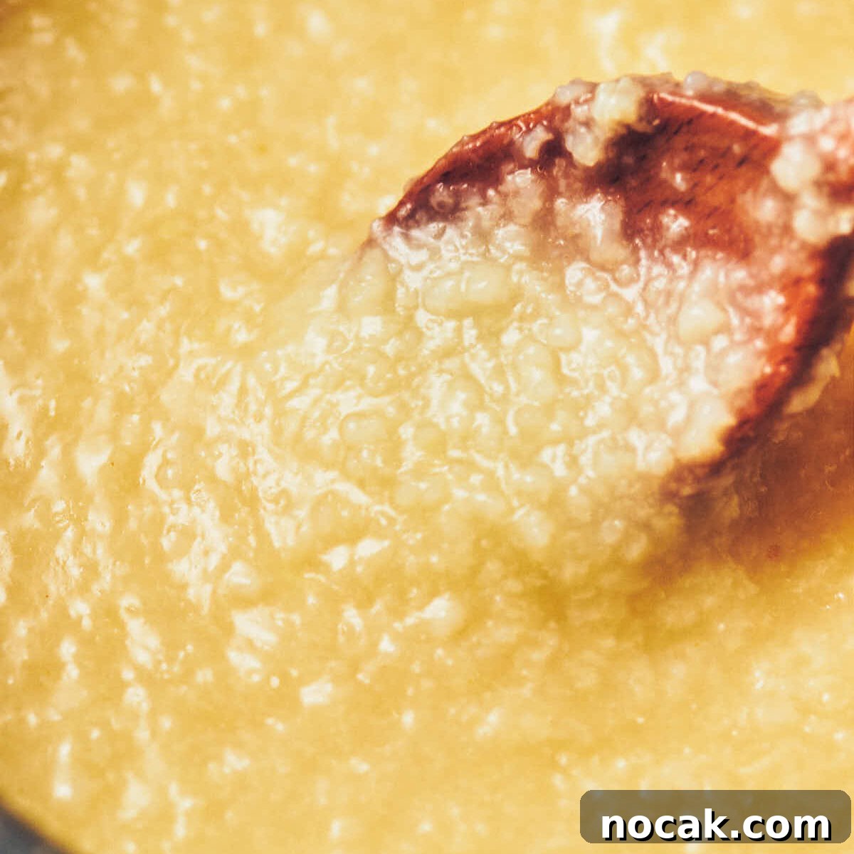 A spoon stirring vegan congee that's been cooked and is ready to serve