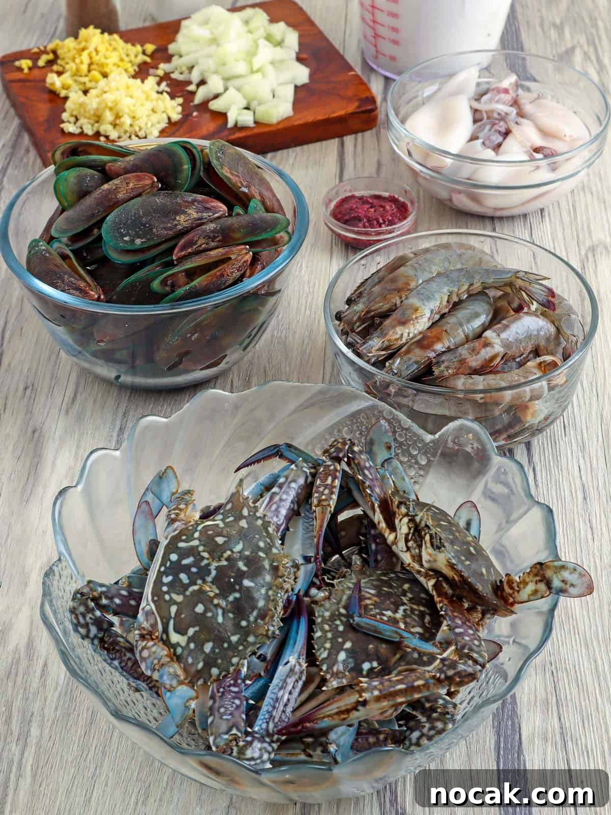 Seafood in Coconut Milk (Ginataang Seafood) Recipe 3 uncooked crab, shrimp, mussels, squid, minced garlic, chopped onions, shrimp paste in bowls