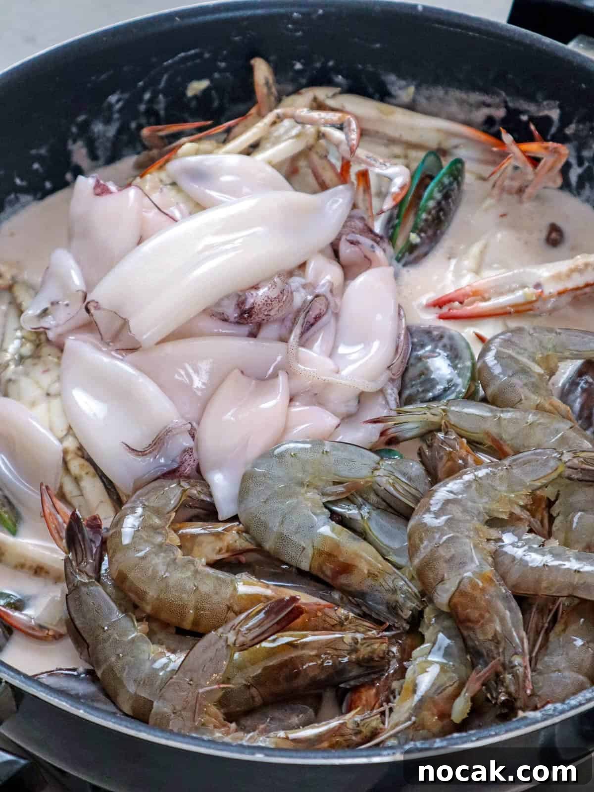 Seafood in Coconut Milk (Ginataang Seafood) Recipe 5 cooking shrimp, squid, crab, and mussels in a coconut sauce in a wide pan