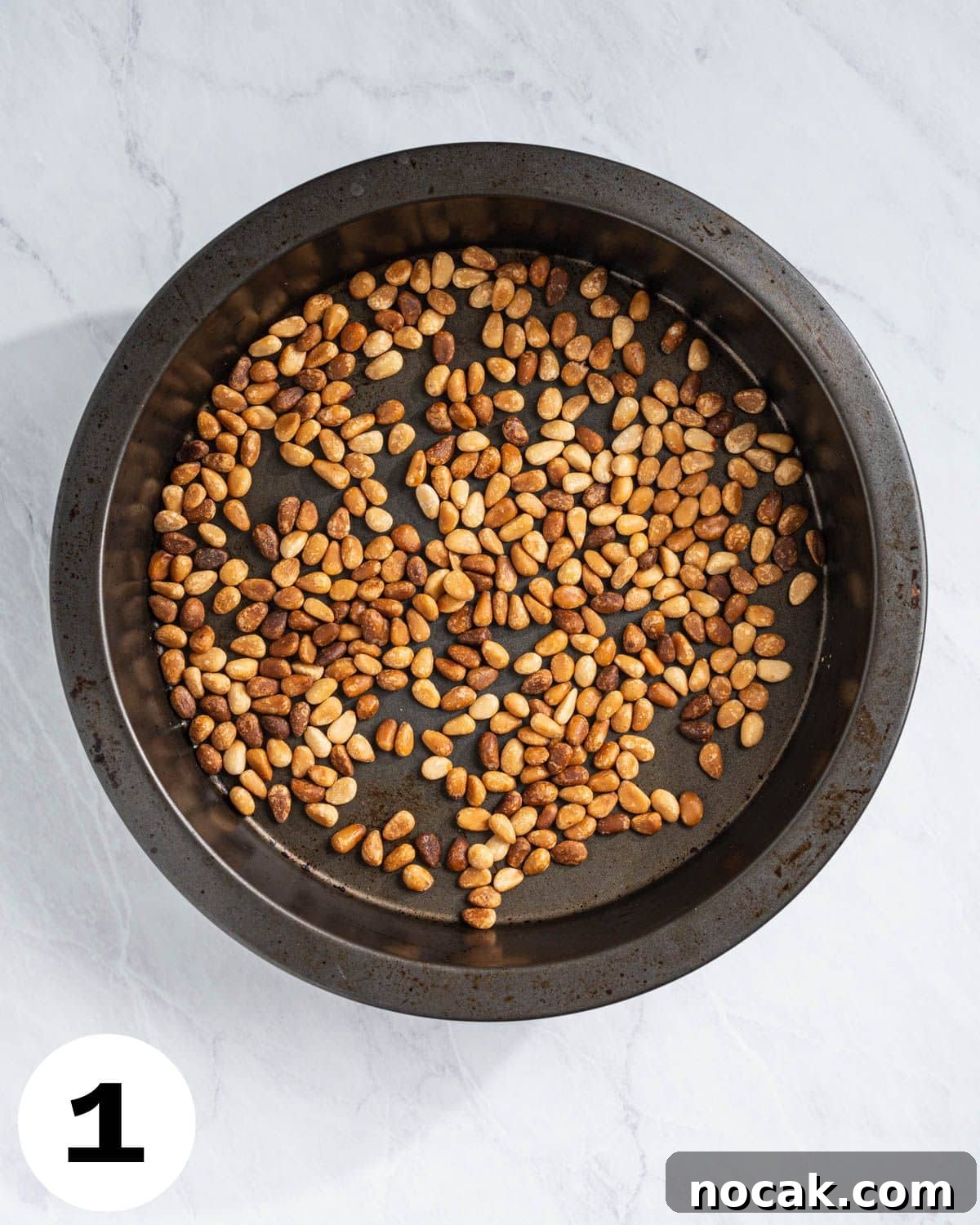 Step 1: Toasted pine nuts in a round pan.