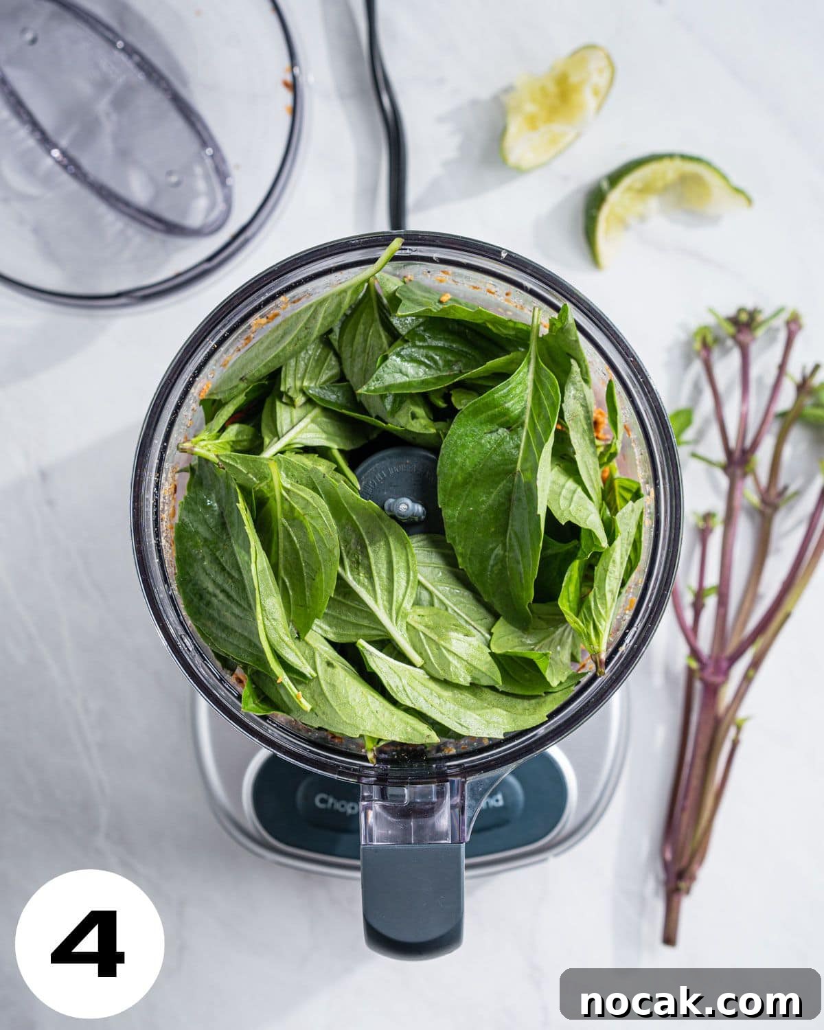 Step 4: Food processor with chopped pine nuts on the bottom and Thai Basil on top.