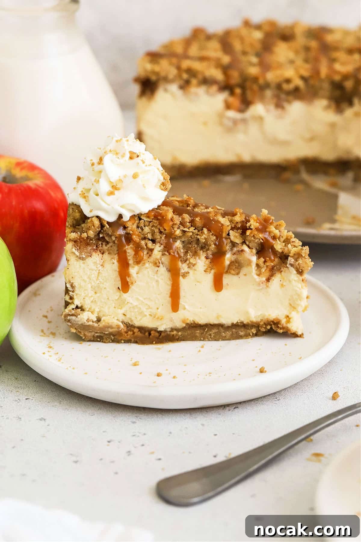 slice of gluten-free caramel apple crumble cheesecake topped with whipped cream