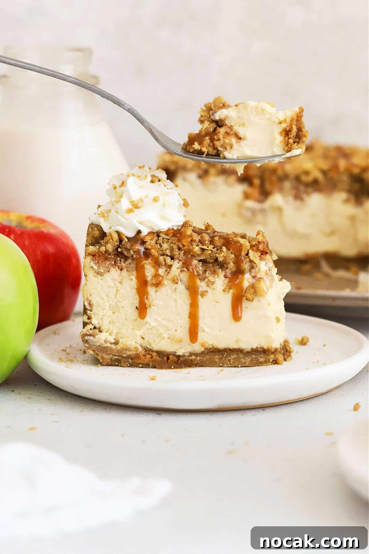 Gluten-Free Caramel Apple Cheesecake Recipe 8 a fork getting a bite from a slice of gluten-free caramel apple crumble cheesecake