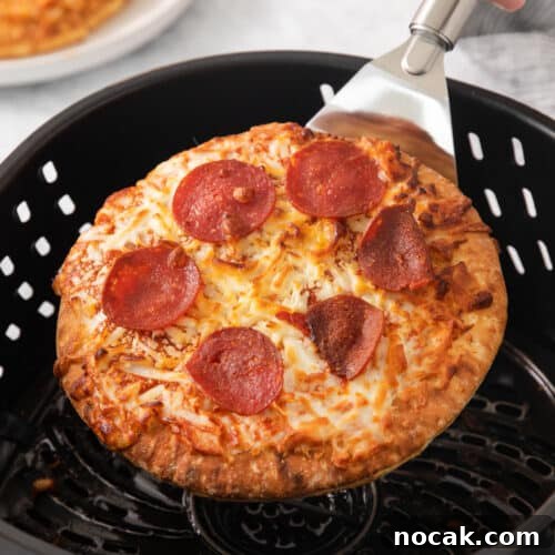 Crispy Frozen Pizza in the Air Fryer in 10 Minutes 2 Frozen pizza coming out of the air fryer.