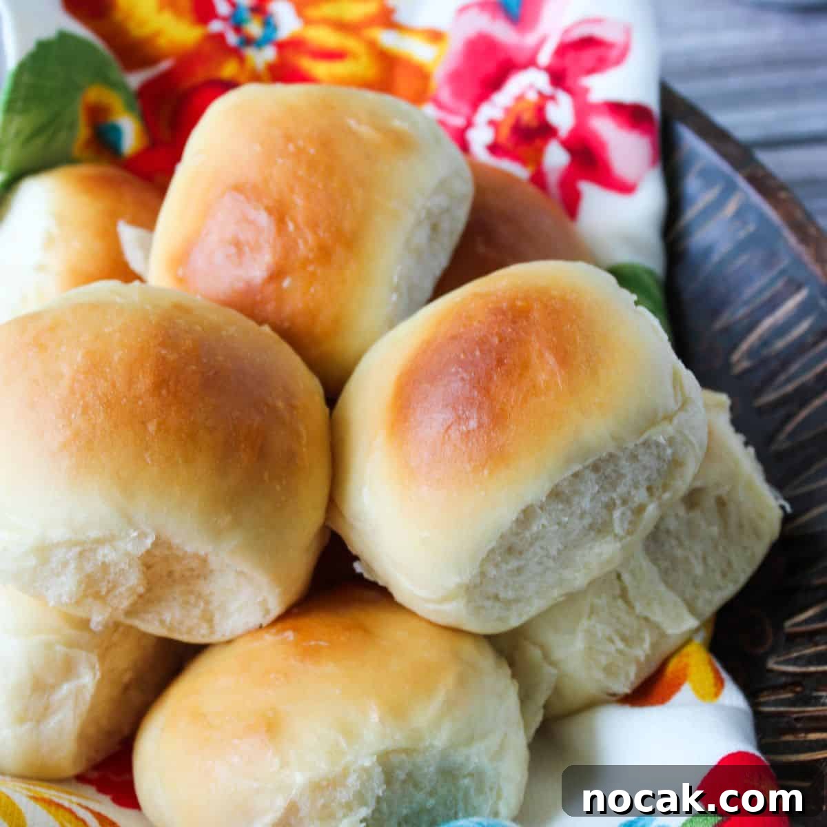 How to Meal Prep Your Thanksgiving Dinner 5 Dinner rolls in a bowl with a flowery towel.