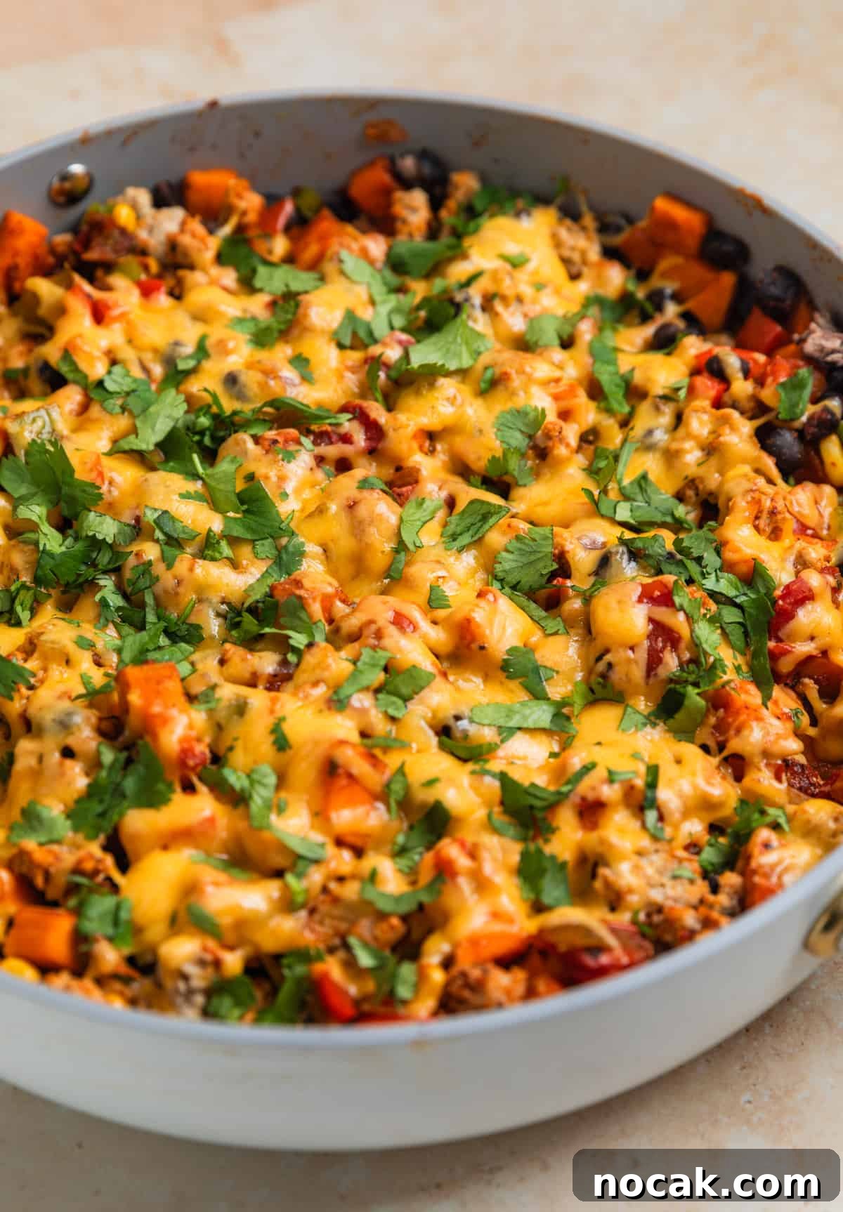 One-Pan Ground Turkey and Sweet Potato Skillet 10 Cheese melted over top of skillet dinner with chopped cilantro over top.