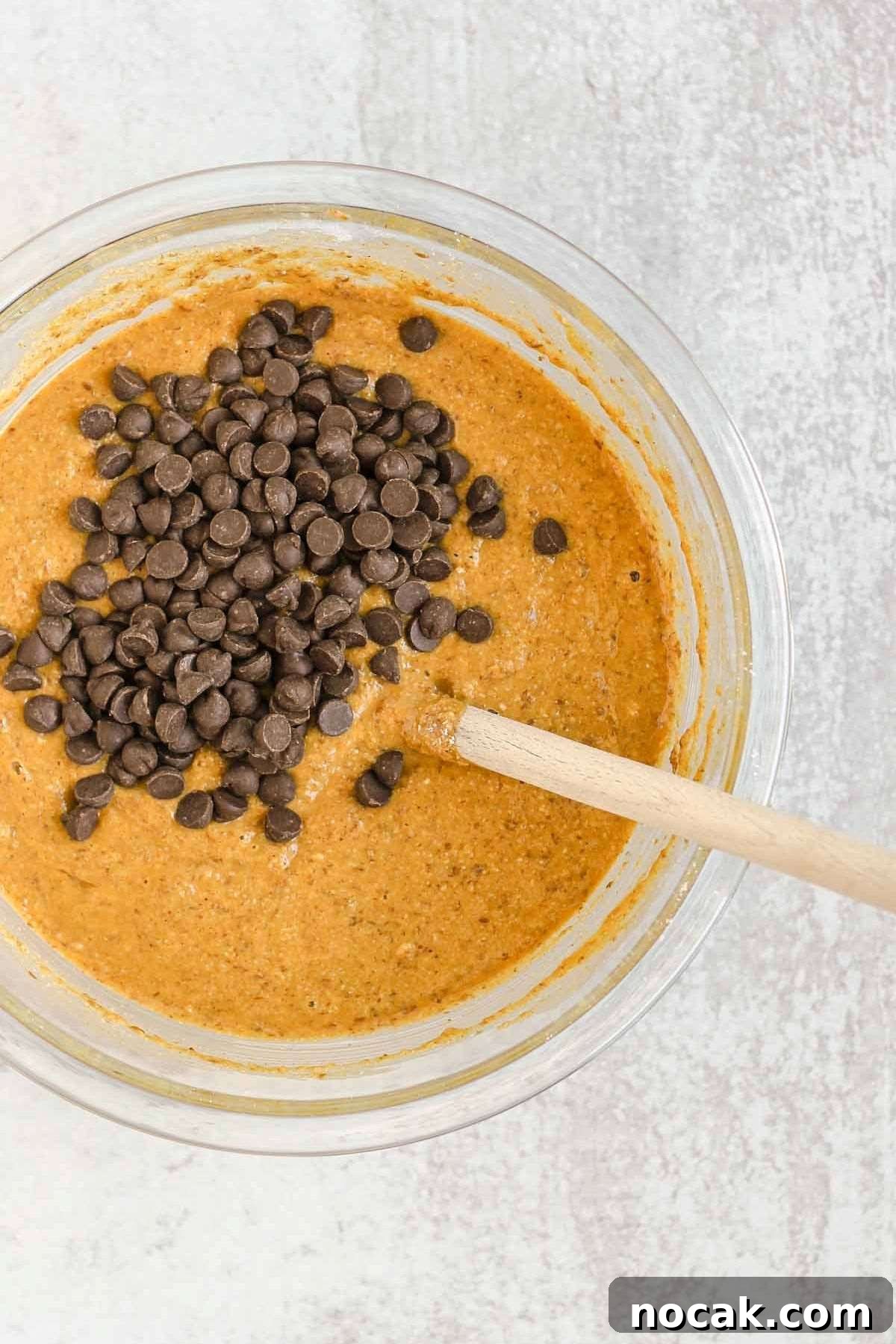 Glass mixing bowl with pumpkin bread batter and chocolate chips.