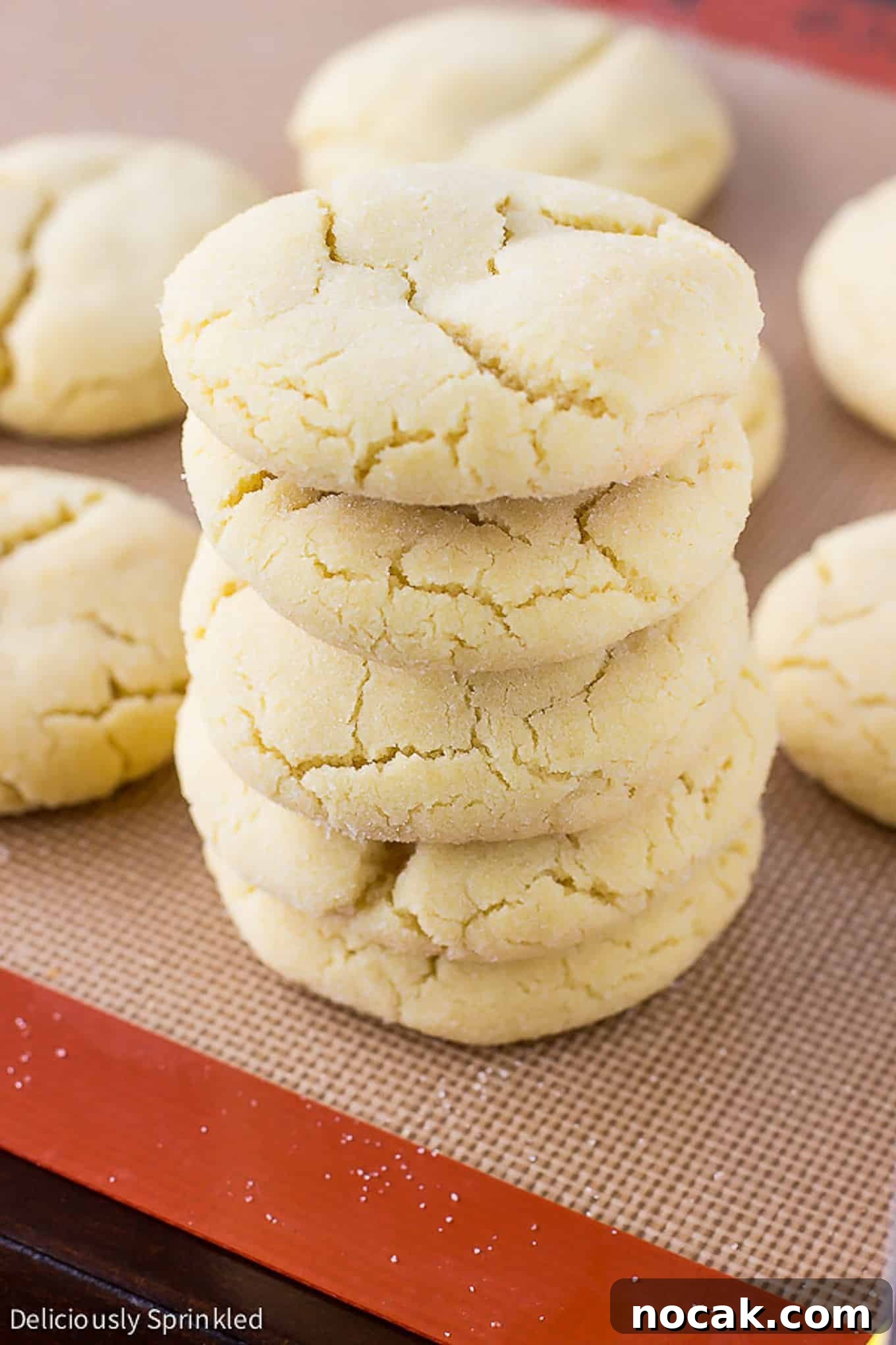 Classic Soft Sugar Cookies Recipe 5 A stack of five sugar cookies on the front corner of a baking tray with more cookies in the background.