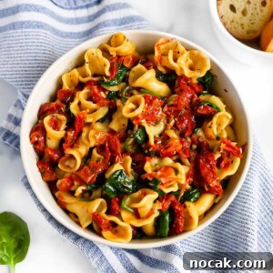 Creamy Tuscan Garlic Pasta with Sun Dried Tomatoes 8 Cooked pasta with a spinach, tomato sauce on top.