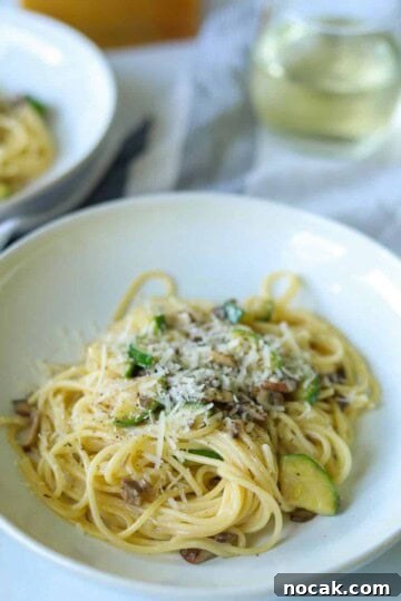 bowl of mushroom zucchini pasta topped with cheese